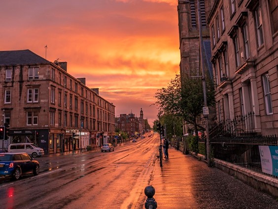 Photo of a street in Glasgow with a sunset in the background